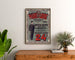 Vintage reclameposter Au Phare de la Loire, kleding, ingelijst boven een houten ladekast, tussen planten.
