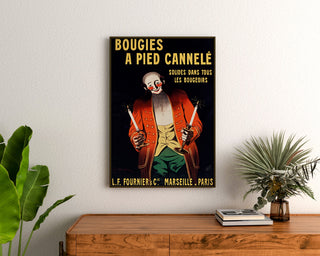 Vintage reclameposter Bougies Fournier, ingelijst boven een houten dressoir tussen planten.
