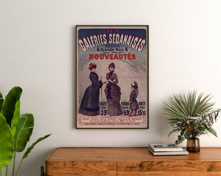 Vintage reclameposter Galeries sedanaises, Nouveautés, ingelijst boven een houten dressoir tussen planten.