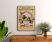 Vintage toeristenposter – Amsterdam, Marken en Volendam, ingelijst boven een houten dressoir tussen planten.
