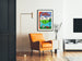 Vintage toeristische affiche – L’Ain touristique, ingelijst in een woonkamer met een oranje fauteuil en een vloerlamp.