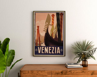 Vintage reisposter – Venezia, gondelboegen, ingelijst boven een houten dressoir, tussen planten.