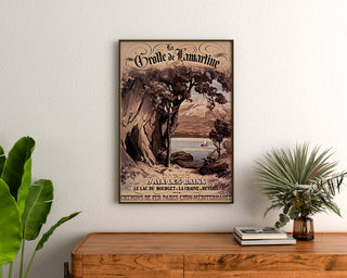 Vintage poster Aix-les-Bains, Grotte de Lamartine, ingelijst boven een houten dressoir tussen kamerplanten.