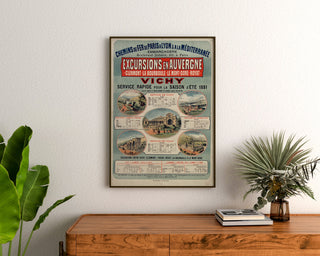 Vintage poster Auvergne, excursions PLM, ingelijst boven een houten dressoir, tussen planten.