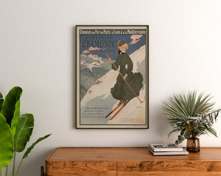 Vintageposter Chamonix, wintersport PLM, ingelijst boven een houten dressoir tussen planten.