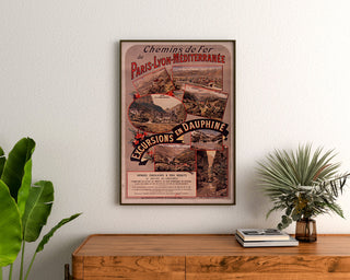 Vintage poster Dauphiné, excursies PLM, ingelijst boven een houten ladekast, tussen planten.