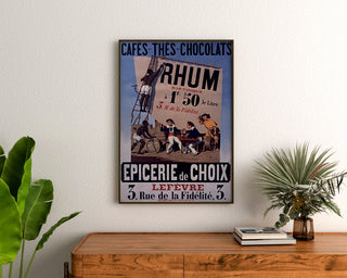Vintage poster Épicerie Lefèvre, coffees and chocolates, framed above a wooden dresser, between plants.