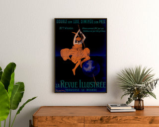 Vintage affiche La Revue illustrée, ingelijst boven een houten dressoir, tussen planten.
