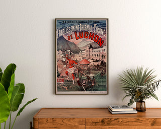 Vintage poster Luchon, casino en kuur, ingelijst boven een houten dressoir, tussen planten.