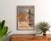 Vintage affiche Nancy, Chemins de fer de l’Est, ingelijst boven een houten dressoir, tussen planten.