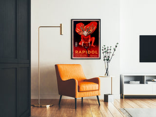 Vintage poster Rapidol, ingelijst in een woonkamer met een oranje fauteuil en een staande lamp.