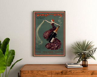 Vintage poster Woman and Wine, Princess’s Theatre, framed above a wooden dresser, flanked by plants.